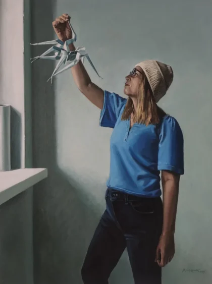 Kobieta w niebieskim polo wpatrująca się w trzymane w dłoni origami