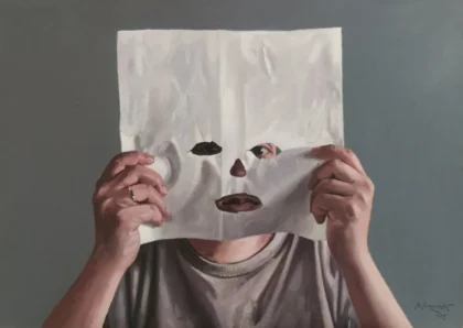 Osoba z twarzą ukrytą za trzymaną białą kartką papieru z wyciętymi otworami na oczy, nos i usta